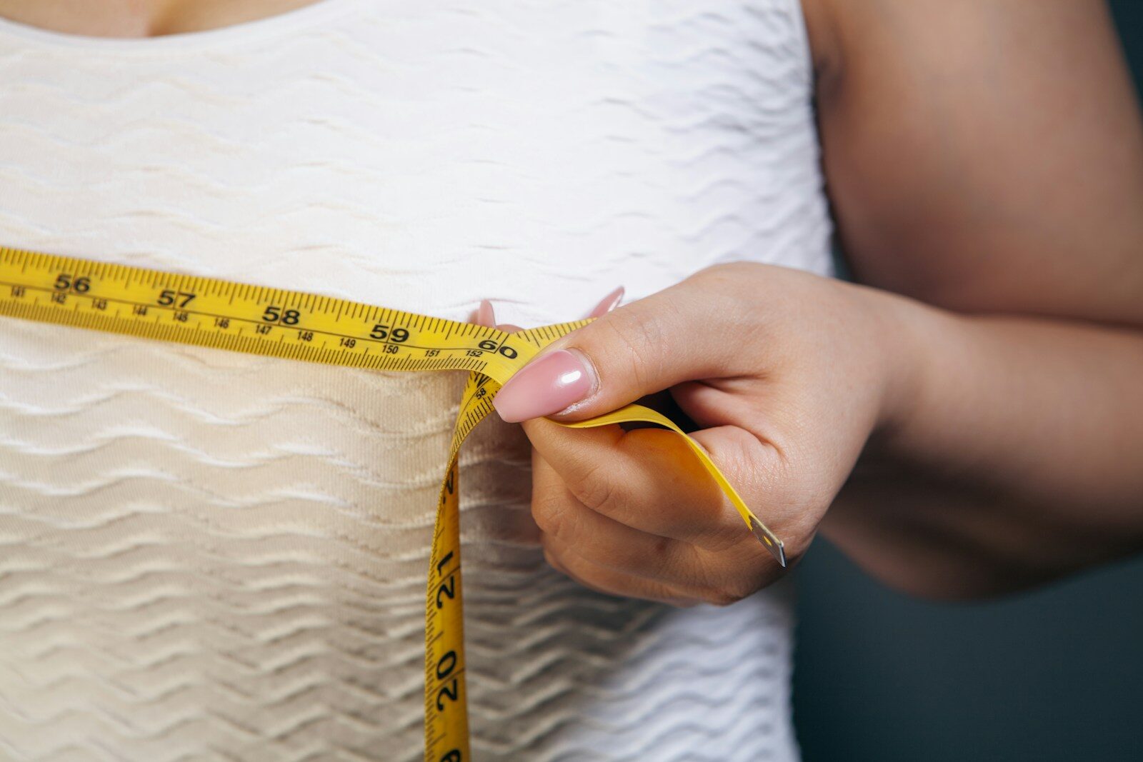 Woman measuring her chest with a tape measure.